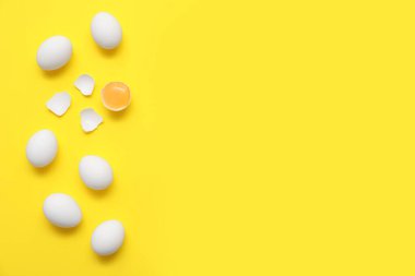 Sarı arka planda tam ve kırılmış tavuk yumurtası.