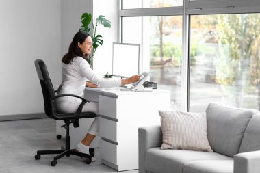 Ofiste telefona bakan genç bir iş kadını. Ulusal İş Günü Pijamalarınızı Giyin