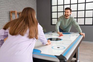 Genç adam evde karısıyla hokey oynuyor.