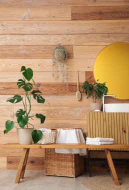 Dolabı, çiçekleri ve ahşap bankı olan şık bir banyo.