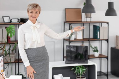 Ofiste bir şey gösteren olgun bir iş kadını portresi.