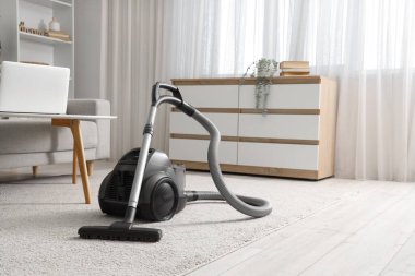 Elektrik süpürgesi ve klozeti olan bir oturma odası.