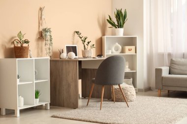 Laptop ve bej duvarın yanındaki ev bitkileriyle modern işyeri