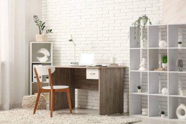 Bilgisayarı ve rafları beyaz tuğla duvarın yanında olan modern ofis.