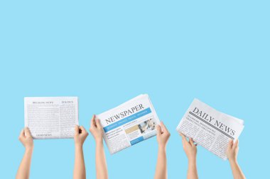 Mavi arka planda sabah gazeteleri olan kadın eller.