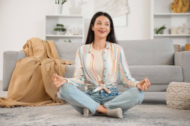 Evinde yerde meditasyon yapan güzel genç bir kadın.