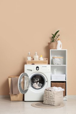 Çamaşır makinesi, sepetleri ve raf ünitesi olan modern çamaşır odasının içi.