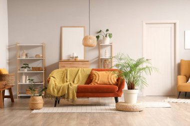 Kırmızı kanepede ekose, raf üniteleri ve bitkilerle oturma odasının içinde.