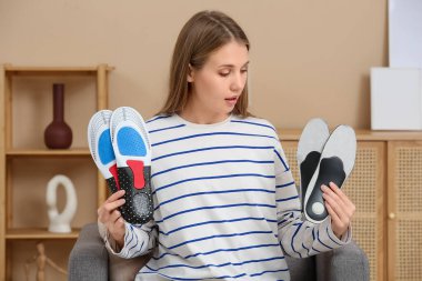 Ortopedik tabanlı genç bir kadın evdeki koltukta oturuyor.