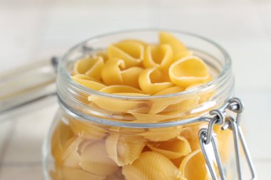 Beyaz karo zemin üzerinde çiğ koni makarna ile kavanoz