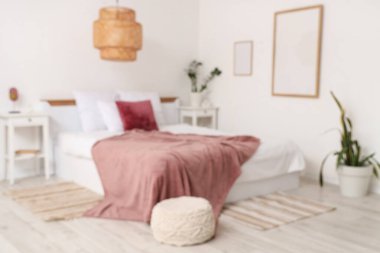 Modern yatak odasının içinde bitkiler, komodinlerin yanında yatağın üzerinde mor bir battaniye.