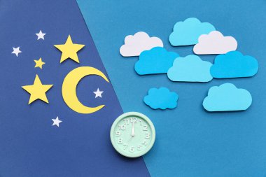 Kağıt bulutlu çalar saat, mavi arka planda yıldızlar ve ay. Melatonin kavramı