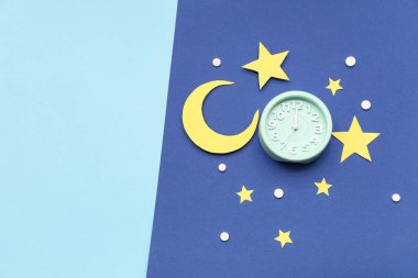 Kağıt yıldızlı çalar saat, ay ve mavi arka planda uyku hapları. Melatonin kavramı