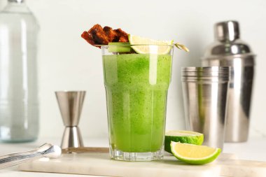 Mermer kesim tahtası, domuz pastırması, limon ve kereviz ile süslenmiş bir bardak Bloody Mary kokteyli.