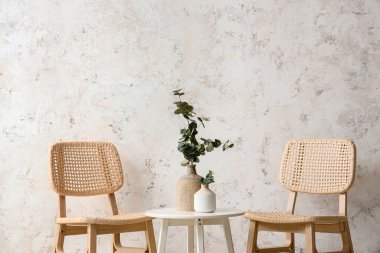 Kahve masalı rahat ahşap sandalyeler ve beyaz grunge duvarının yanında okaliptüs dalları.