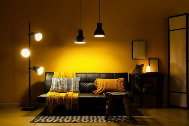 Modern siyah kanepesi, sehpası ve geceleri parlayan lambaları olan şık bir oturma odası.