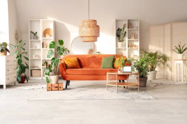 Kahverengi kanepesi, çiçekleri, sehpası ve aynası olan şık bir oturma odası.