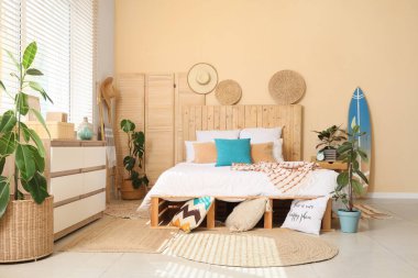 Rahat yatağı, sörf tahtası ve çiçekleri olan şık bir yatak odası.