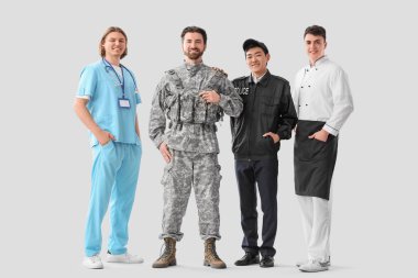 Aydınlık arkaplanda farklı mesleklerden üniformalı bir grup genç adam.