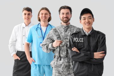 Aydınlık arkaplanda farklı mesleklerden üniformalı bir grup genç adam.