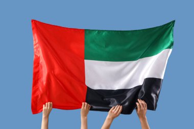 Mavi arka planda BAE bayrağı olan kadın eller