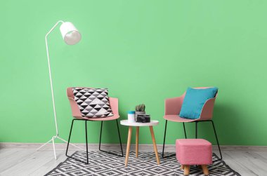 Oturma odasının içinde sandalyeler, sehpa ve lamba var.