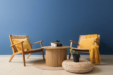 Oturma odası, koltuklar, kahve masası ve bitkiler.