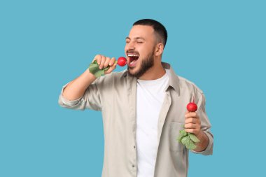 Genç adam mavi arka planda olgun turp yiyor.