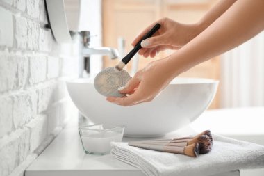 Makyaj fırçasını banyoda aletle yıkayan kadın elleri, yakın plan.