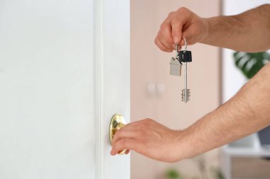 Odanın kapısını açan anahtarı olan erkek eller, yakın plan.