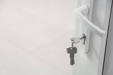 Açık metal plastik kapıdaki evden anahtar, yakın plan.