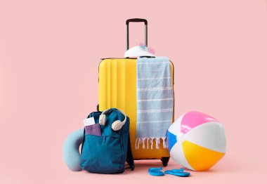 Çanta, sırt çantası, şişirilebilir top ve pembe arka planda plaj aksesuarları.