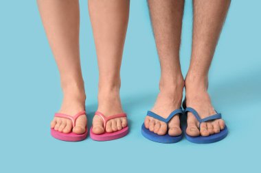 Mavi arka planda şık parmak arası terlikler giyen genç kadınların bacakları