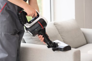 Oda temizleme koltuğunda modern elektrikli süpürgeyle çalışan erkek hademe.