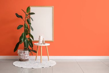 Odanın içindeki turuncu duvarın yanındaki masa ve bitki örtüsü.