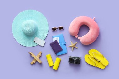 Cep telefonu, güneş kremi şişeleri ve leylak arka planda plaj aksesuarları.