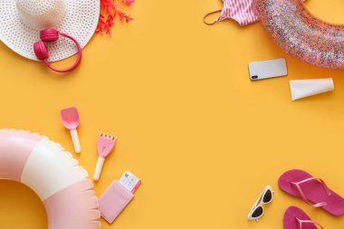 Sarı zemin üzerinde şişirilebilir halkalar, cep telefonu ve plaj aksesuarlarından yapılmış çerçeve