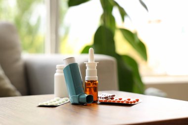 Modern astım spreyi, haplar ve ilaçlar oturma odasındaki sehpanın üzerinde, yakın plan.