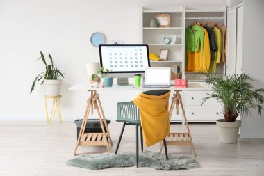 Modern dizüstü bilgisayarı, bilgisayarı ve takvimi aydınlatma odasının içinde olan şık bir iş yeri