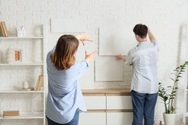 Erkek arkadaşıyla birlikte beyaz tuğla duvara resim yapan genç bir kadın.