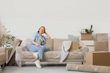 Odadaki koltukta kutuları taşıyan genç bir kadın.