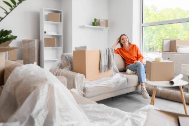 Odadaki koltukta kutuları taşıyan genç bir kadın.