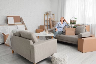 Odadaki koltukta oturan taşınma kutusuyla genç bir kadın.