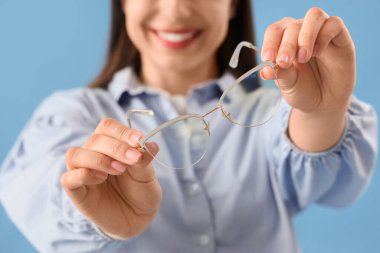 Mavi arka planda gözlüklü genç bayan, yakın plan.