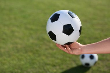 Yeşil stadyumun arka planında futbol topu tutan erkek el.