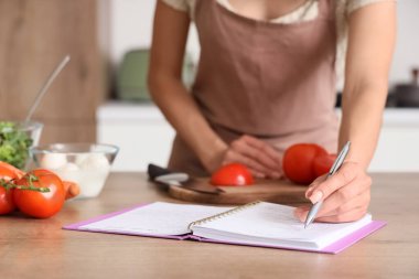 Yemek tarifini evdeki masaya yazan genç bir kadın, yakın plan.