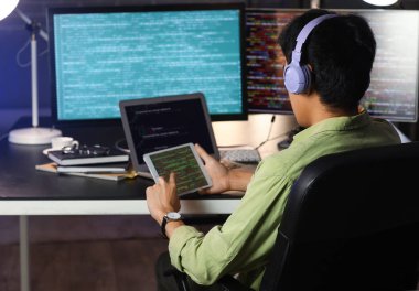Erkek programcı, gece ofiste tablet bilgisayarla çalışıyor.