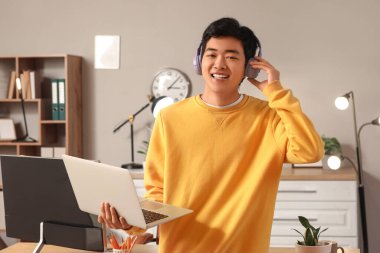 Kulaklık ve dizüstü bilgisayarlı Asyalı erkek programcı