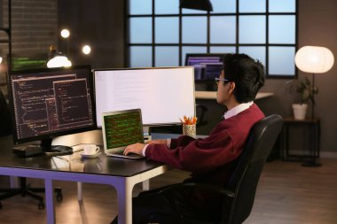 Erkek programcı geç saatlerde bilgisayarla çalışıyor.