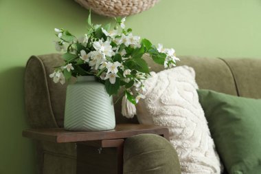 Oturma odasının içinde kanepe ve vazoyla çiçek açmış yasemin çiçekleri, yakın plan.